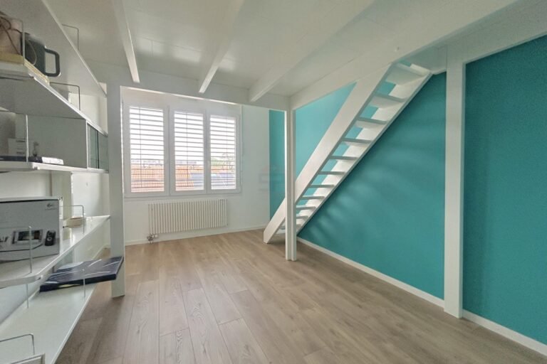 Helles Dachgeschosszimmer mit Treppe und türkisfarbenen Wänden